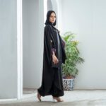 Black Nidha kaftan abaya with purple cuffs and gold butterfly brooch – casual modest wear for Pakistan, Dubai & UK.