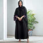 Black Nidha kaftan abaya with purple cuffs and gold butterfly brooch – casual modest wear for Pakistan, Dubai & UK.