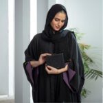 Black Nidha kaftan abaya with purple cuffs and gold butterfly brooch – casual modest wear for Pakistan, Dubai & UK.