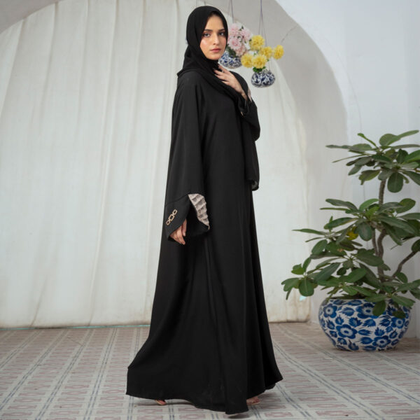 Black Nidha open-front abaya with lace sleeve details and golden brooch – casual modest wear