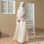 Model wearing Luna Flora Abaya coat set with pastel floral printed outer layer and cream inner dress styled with matching hijab.